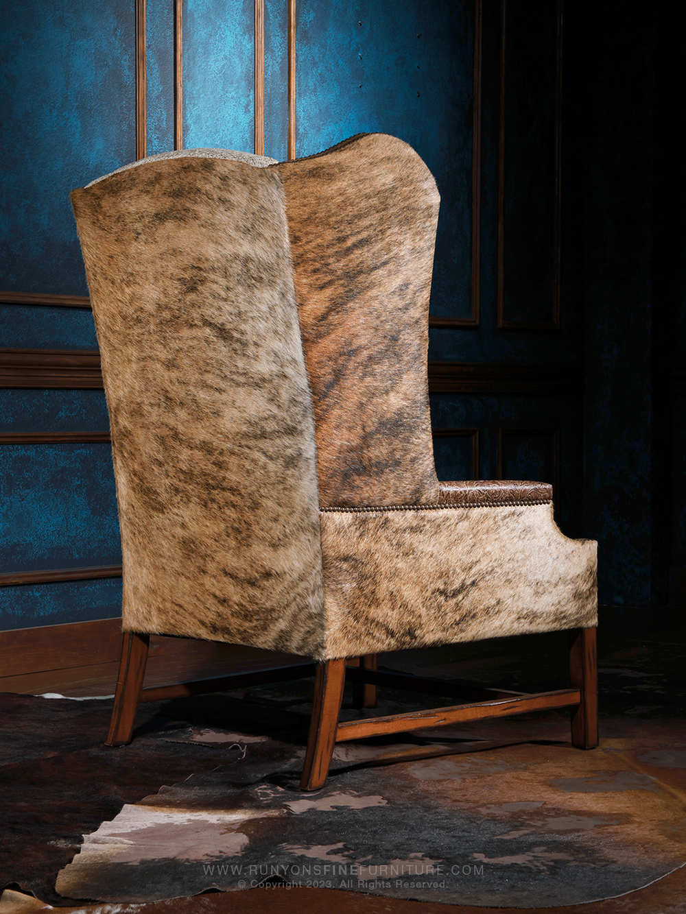 Rear view of a western-inspired high-back accent chair fully upholstered in natural speckled cowhide. Clean lines and a sturdy wooden base give this piece a grounded, handcrafted lodge aesthetic.
