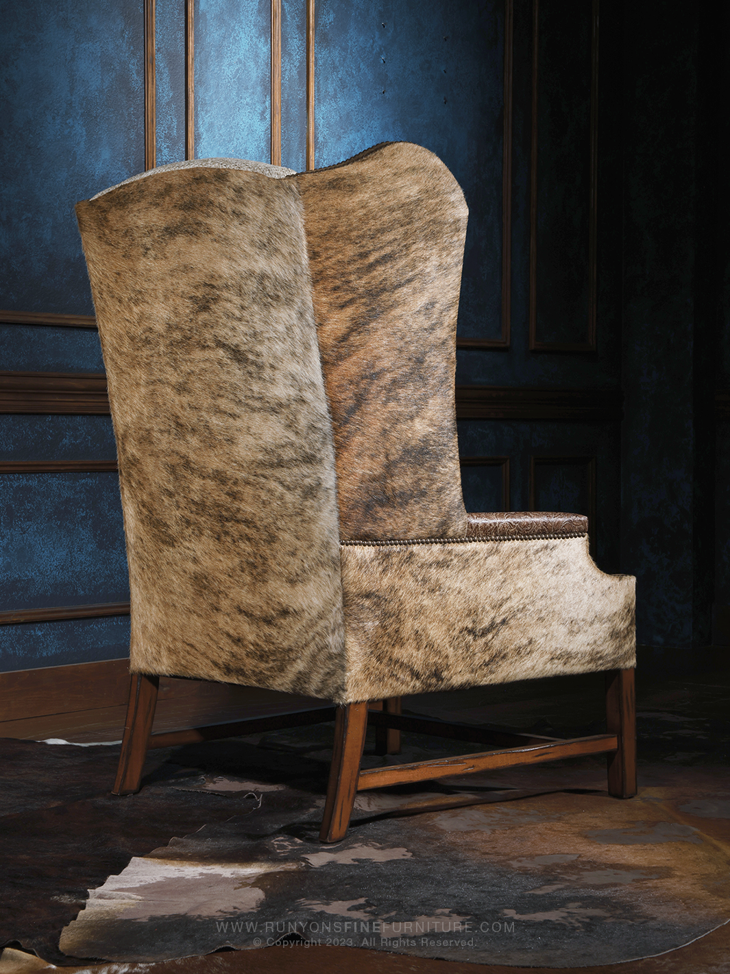 Rear view of a western-inspired high-back accent chair fully upholstered in natural speckled cowhide. Clean lines and a sturdy wooden base give this piece a grounded, handcrafted lodge aesthetic.