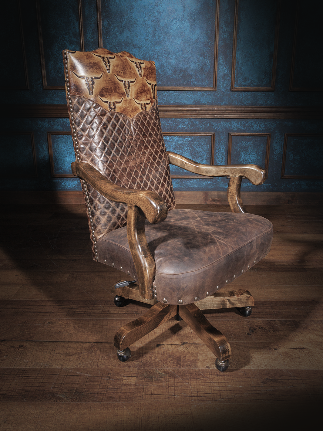 A brown leather desk chair with longhorn embossing and a diamond quilt design, featuring a wooden frame and metal caster wheels.