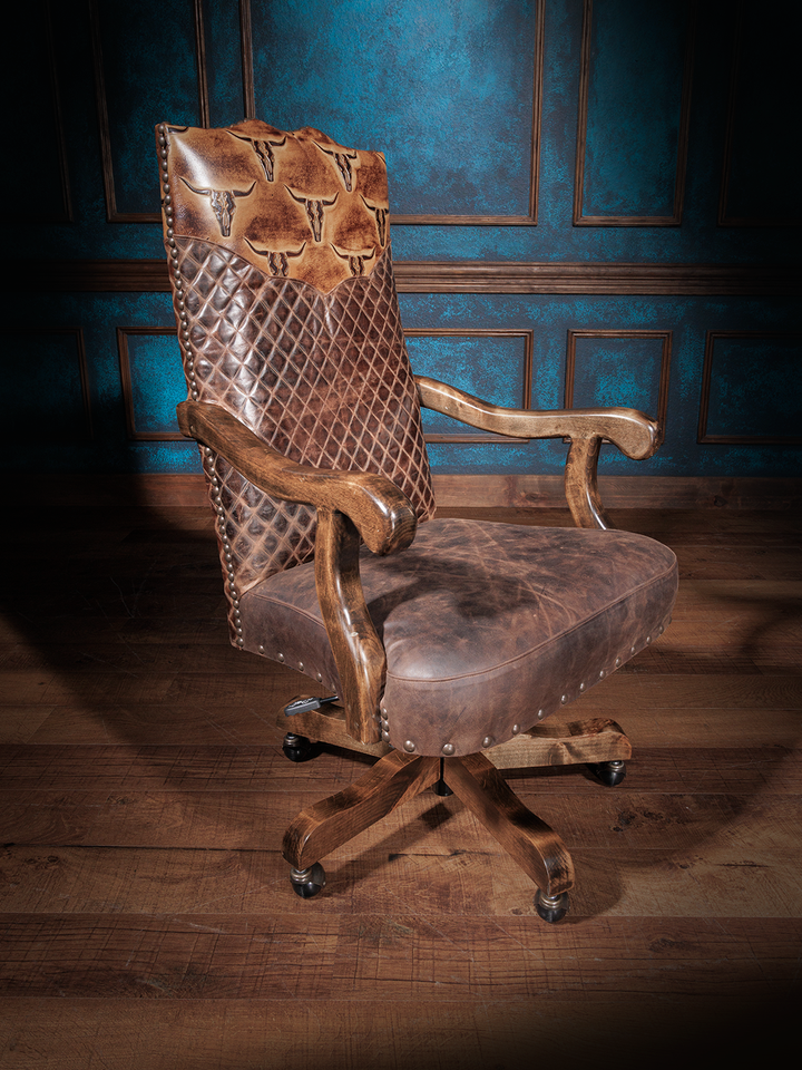 A brown leather desk chair with longhorn embossing and a diamond quilt design, featuring a wooden frame and metal caster wheels.