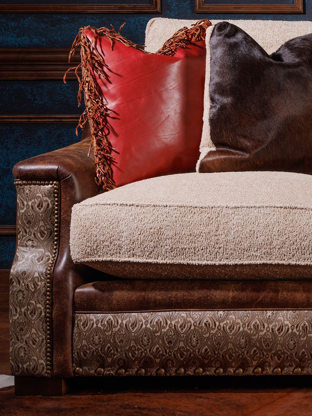 close view of fabric and leather sofa, with fabric cushions, red and hair on hide pillows, leather sides
