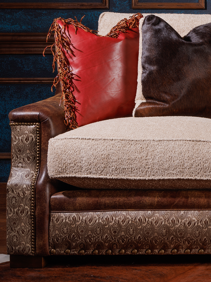 close view of fabric and leather sofa, with fabric cushions, red and hair on hide pillows, leather sides