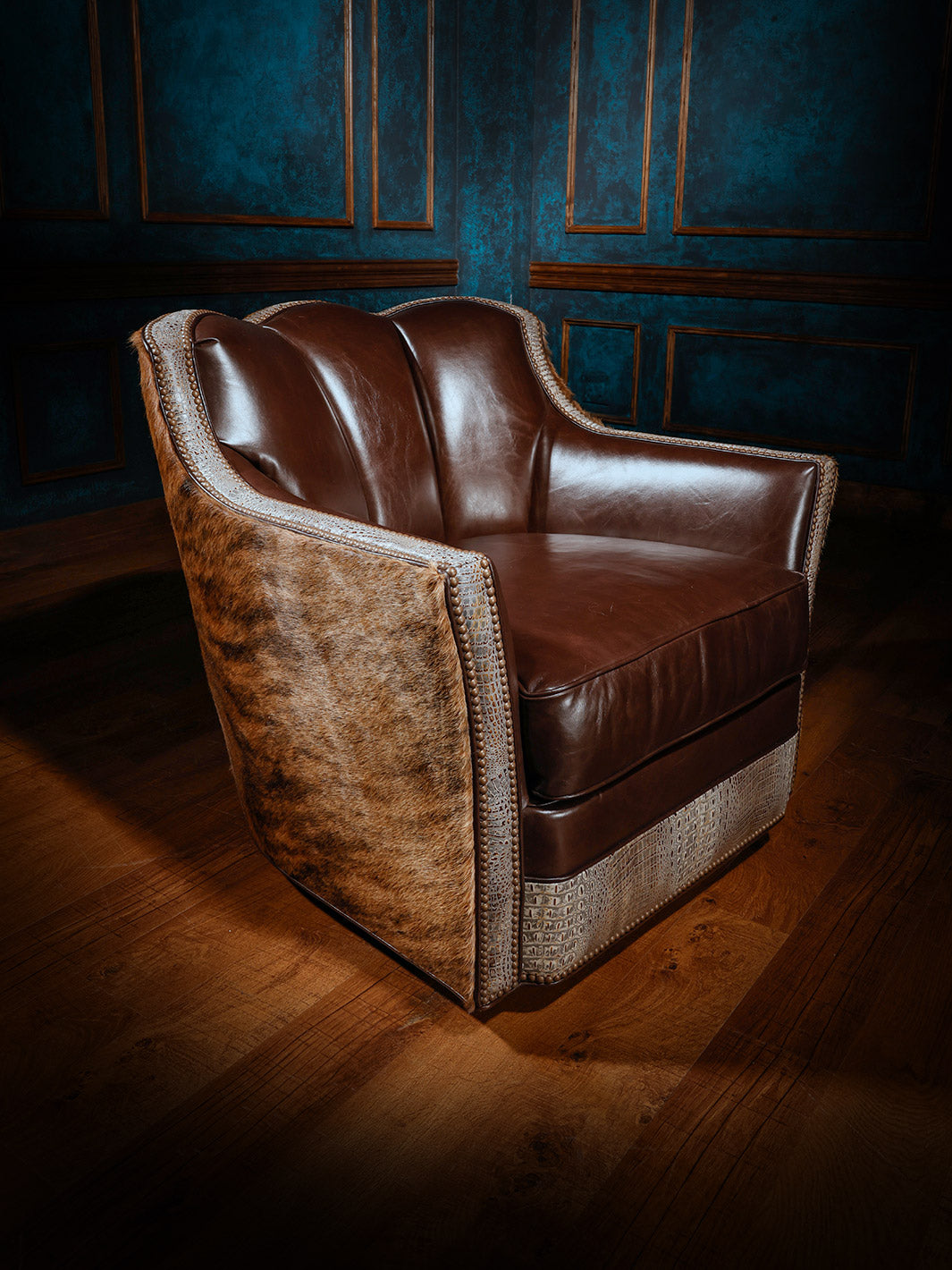 A western-style swivel chair featuring rich brown leather upholstery, hair-on-hide sides, and crocodile-patterned leather accents, complemented by nailhead trim.