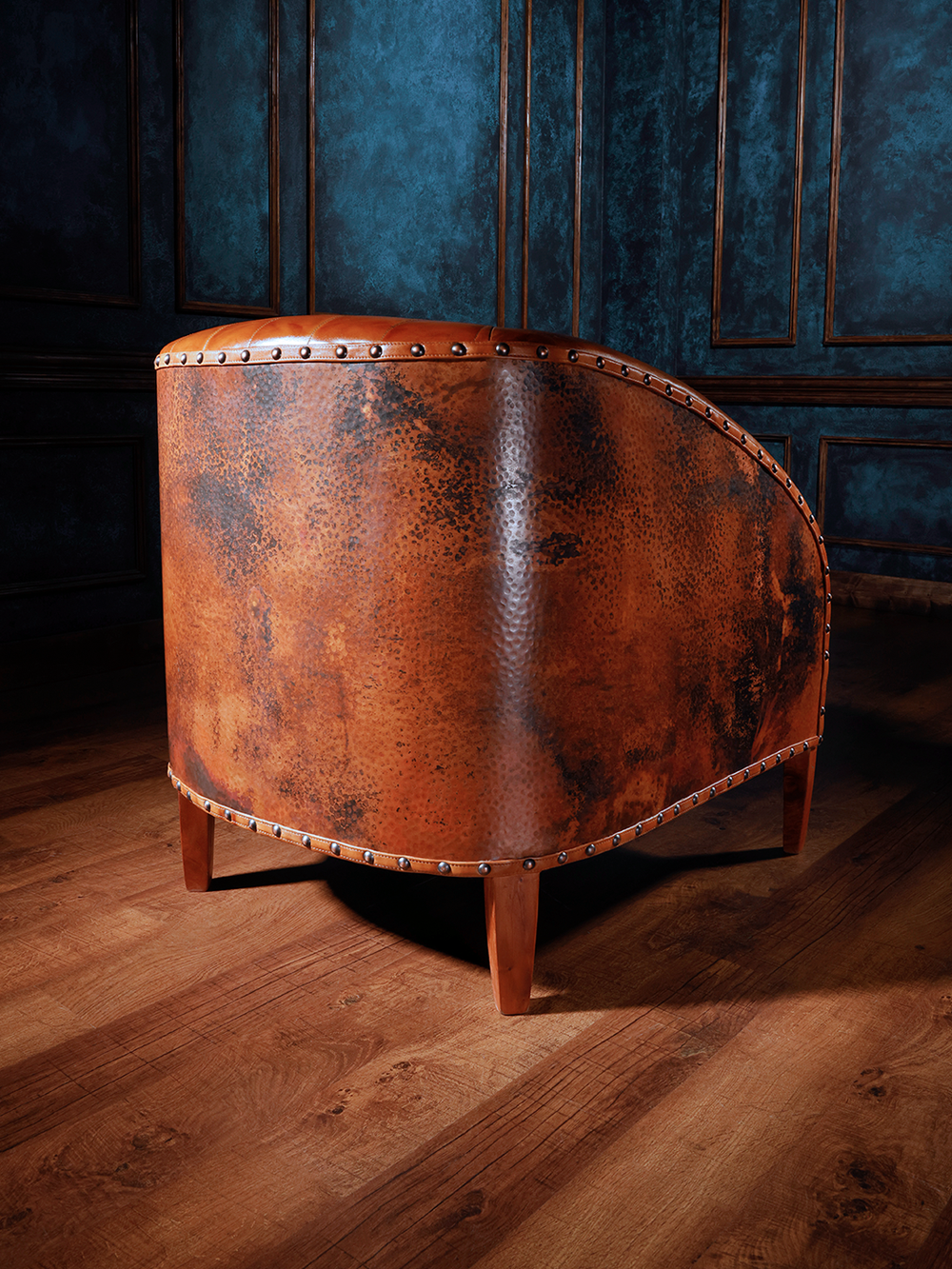 Close-up of the back of the Copper Canyon Accent Chair, highlighting the hand-forged copper back with distinctive rivet detailing, paired with elegant wood legs.