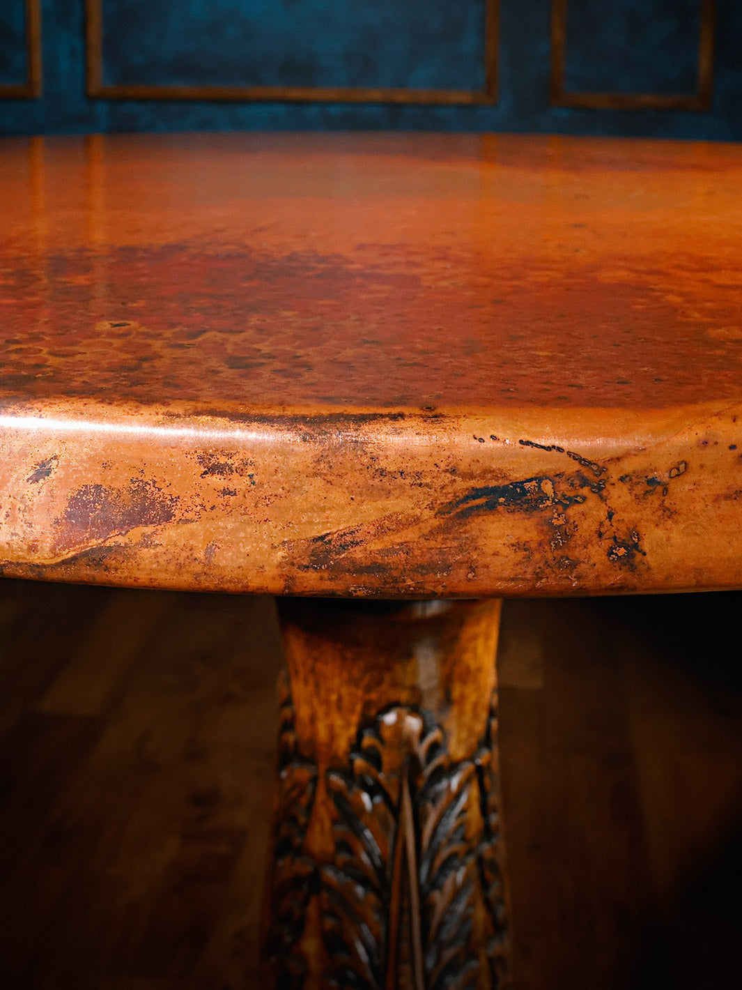 Detail shot of the copper table edge, showing the unique patina variations and organic character of the hand-forged copper surface.