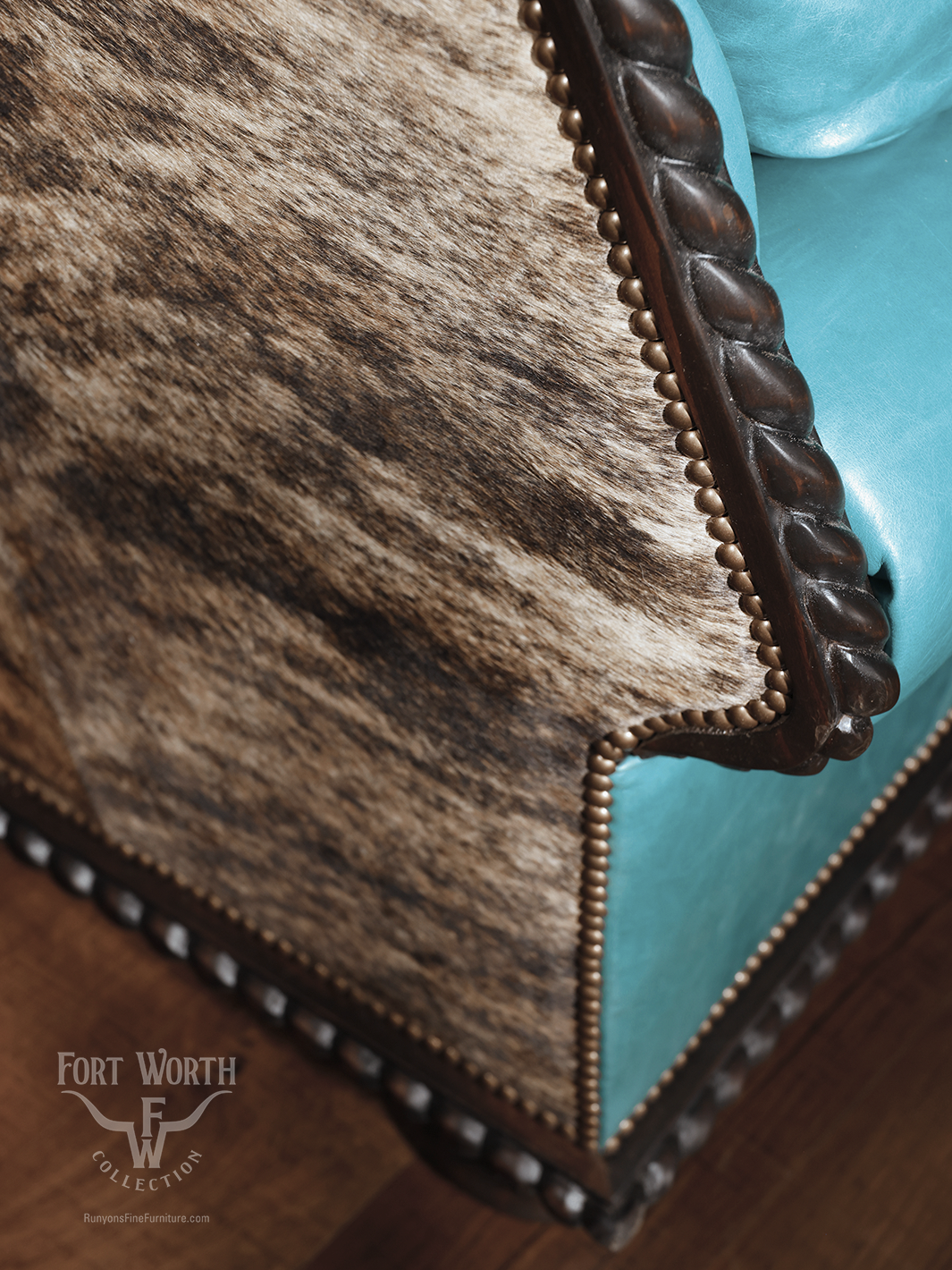 Close-up of a turquoise leather western sofa with cowhide panel and twisted carved wood detailing, highlighting the fine upholstery and nailhead trim.