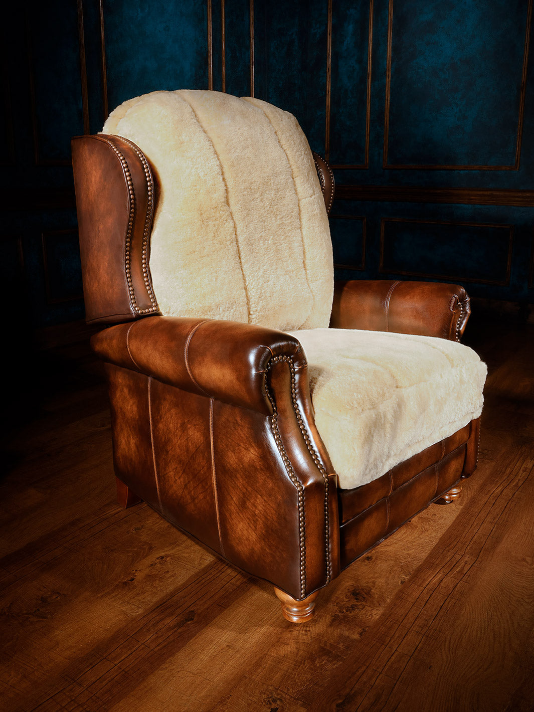 A brown leather recliner with a shearling lined seat cushion and backrest, positioned in a room with a dark blue wall and wooden flooring.