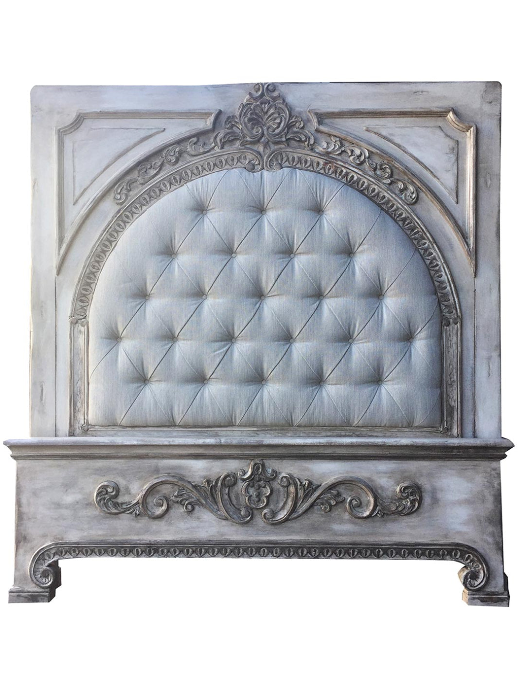 Decorative headboard with tufted upholstered panel and ornate carvings on a white background