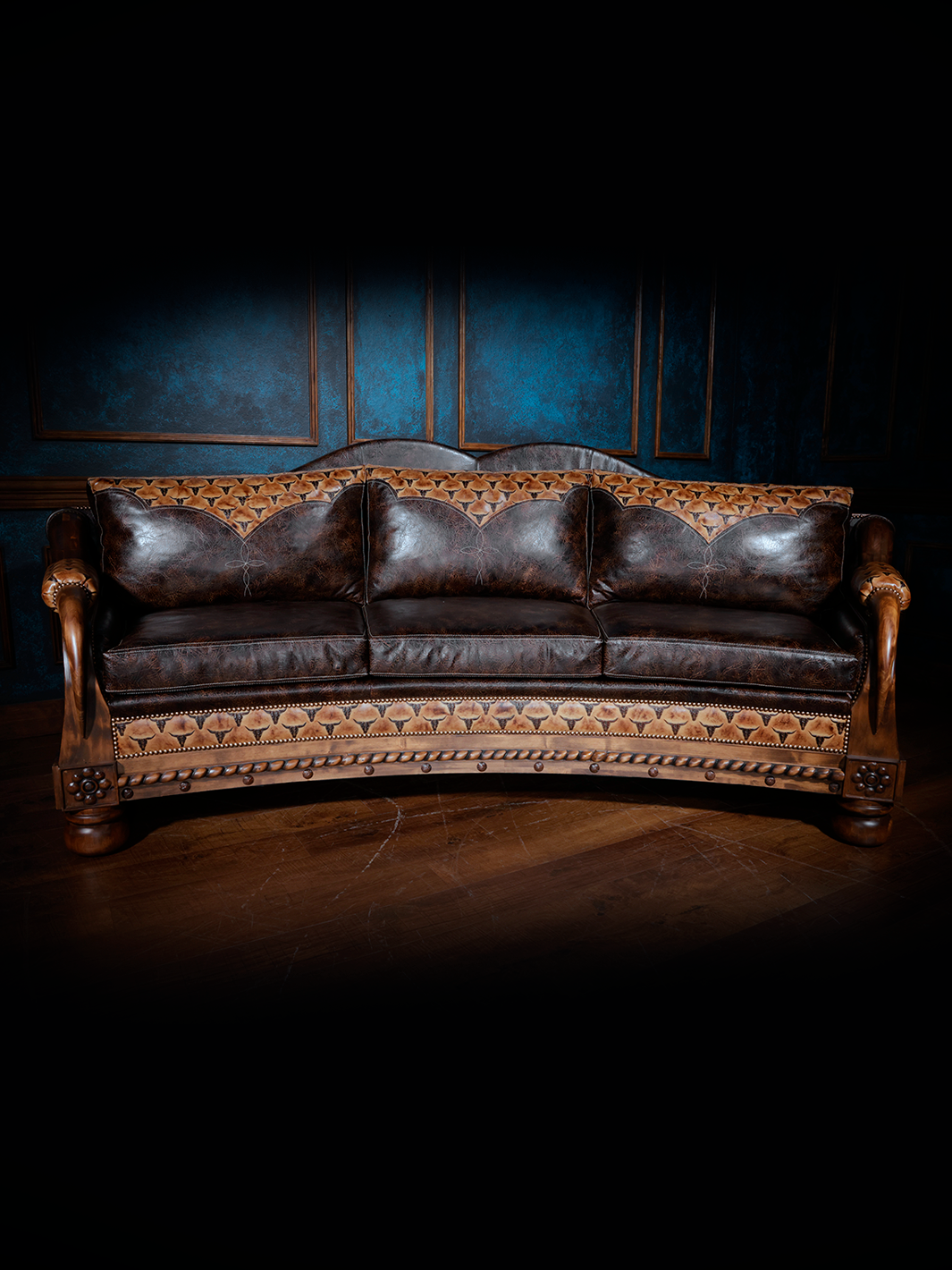 Full front view of a dark brown leather western sofa with detailed tooling and decorative woodwork along the arms and base