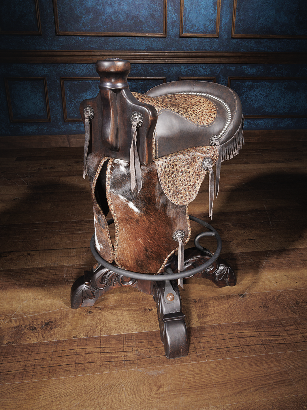 A saddle bar stool with dark brown full-grain leather and mocha-colored genuine leather with ostrich embossing. It features silver-finished conchos, hand tacks, and cowhide in the saddle's fenders, seat, and flaps.