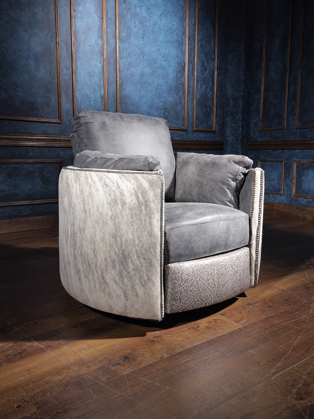 A high-quality combination leather swivel recliner with floral embossed accents, placed in a room with a blue wall and wooden flooring.