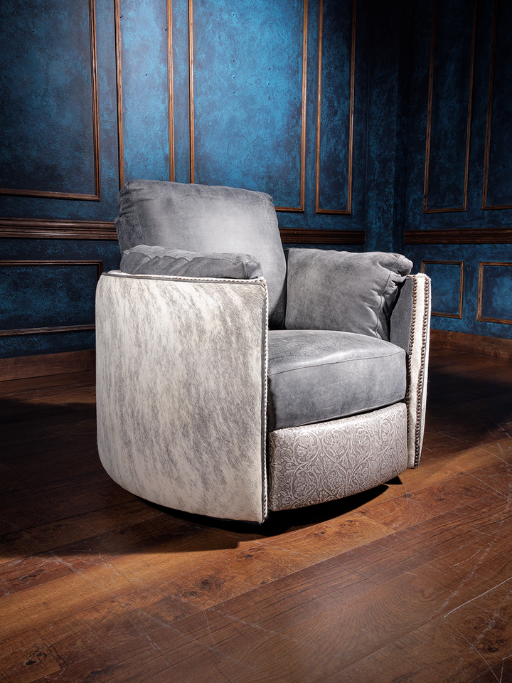 A high-quality combination leather swivel recliner with floral embossed accents, placed in a room with a blue wall and wooden flooring.