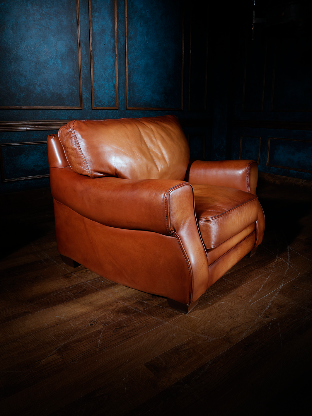 Luxurious Western leather accent chair in saddle tan, shown from a front angle to highlight its plush seat, wide back cushion, and smooth curved arms. The warm-toned leather and generous proportions make it ideal for upscale rustic interiors.