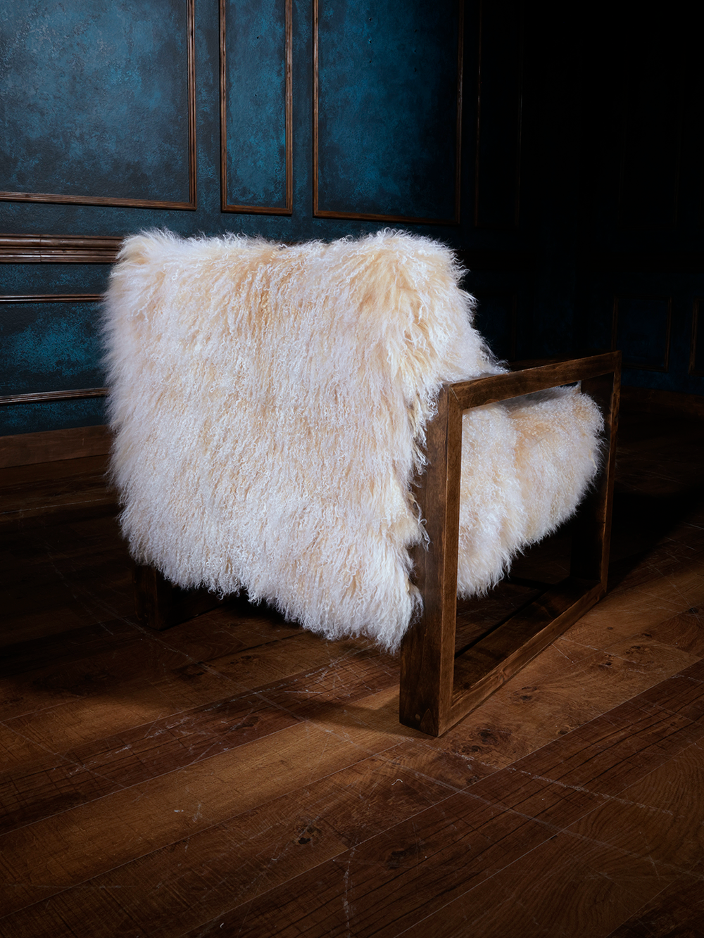 Rear view of a fluffy Tibetan wool chair wrapped in thick, natural sheepskin and framed by clean, squared wood arms. Cozy, sculptural, and ready for a modern mountain retreat.