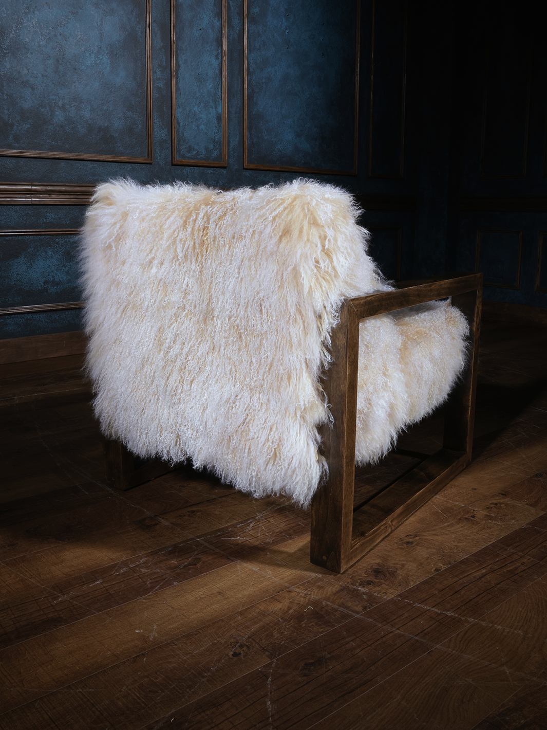 Rear view of a fluffy Tibetan wool chair wrapped in thick, natural sheepskin and framed by clean, squared wood arms. Cozy, sculptural, and ready for a modern mountain retreat.