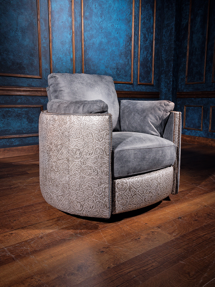A gray leather snug swivel recliner chair placed on a wooden floor with a blue textured wall in the background.