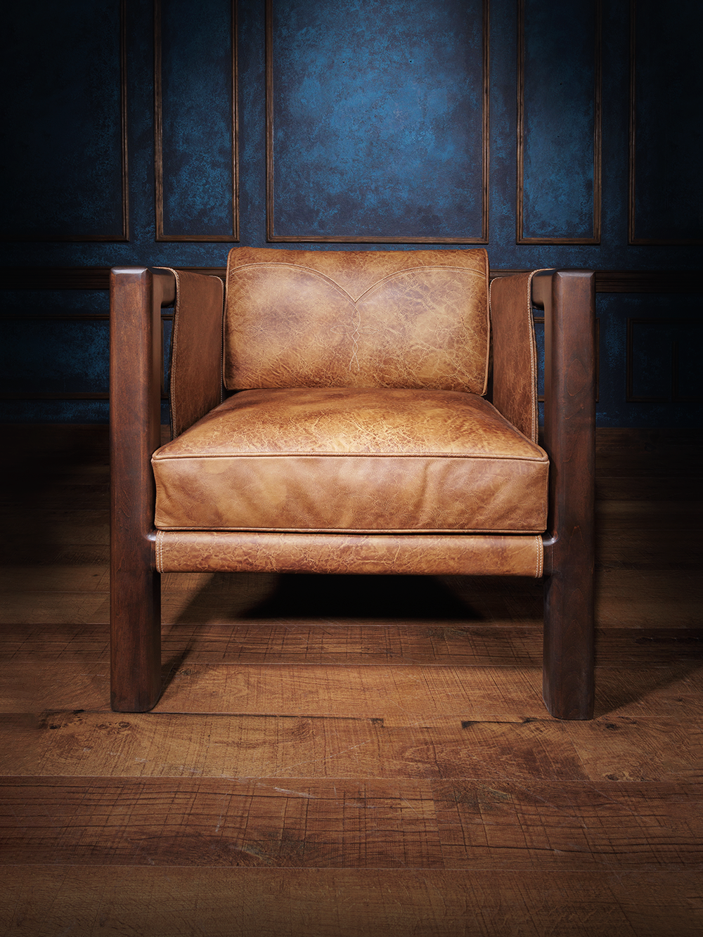 Front view of a Santa Fe-style leather sling chair with thick seat cushions and a deep wood frame. Clean lines and rugged materials deliver a refined take on desert lodge design.