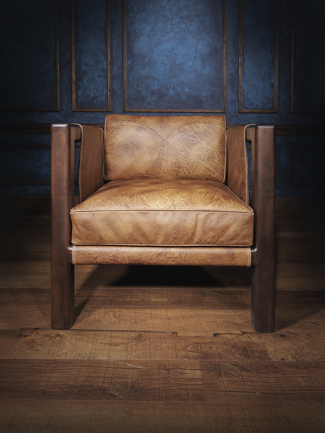 Front view of a Santa Fe-style leather sling chair with thick seat cushions and a deep wood frame. Clean lines and rugged materials deliver a refined take on desert lodge design.