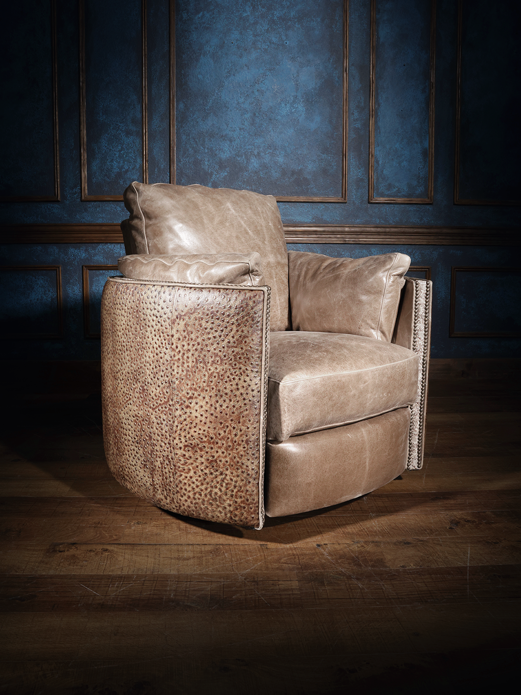 A brown leather swivel recliner with embossed ostrich pattern, positioned in a room with blue walls and wooden flooring.