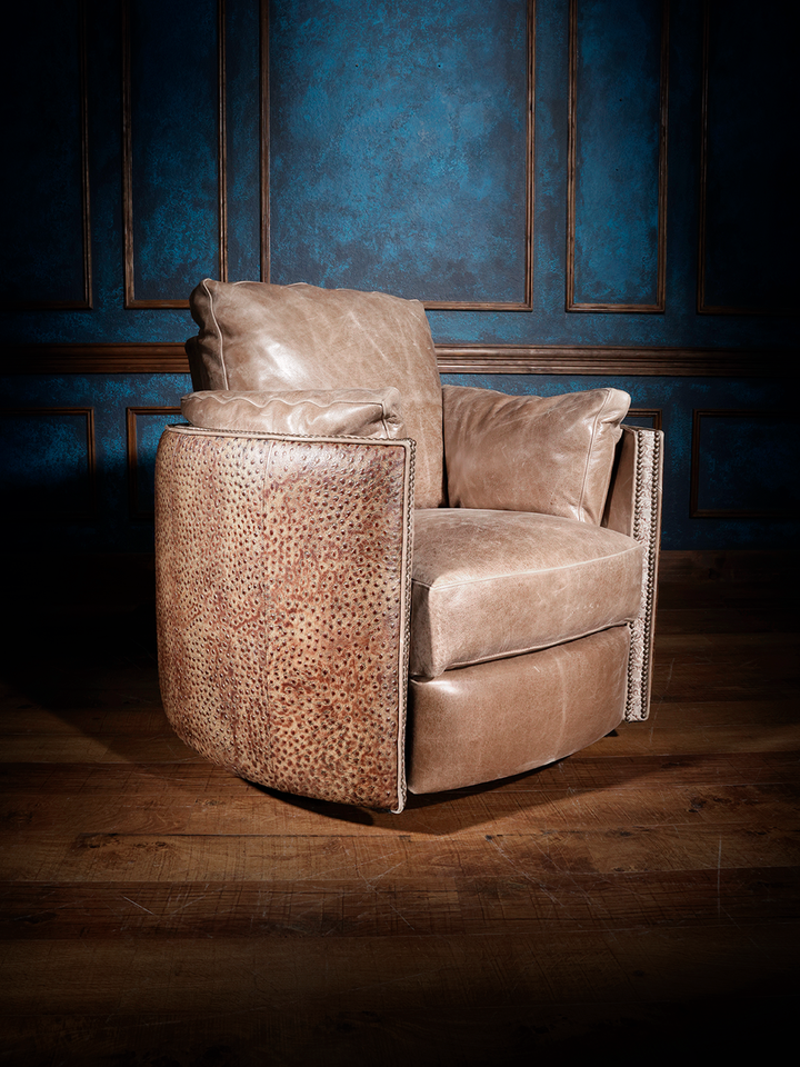 A brown leather swivel recliner with embossed ostrich pattern, positioned in a room with blue walls and wooden flooring.