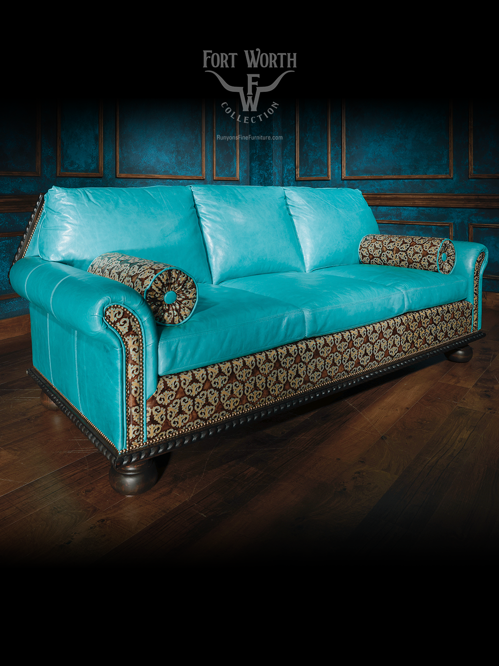 Full view of a turquoise leather western sofa with patterned fabric panels and bolster pillows, framed by nailhead accents and carved wooden base.