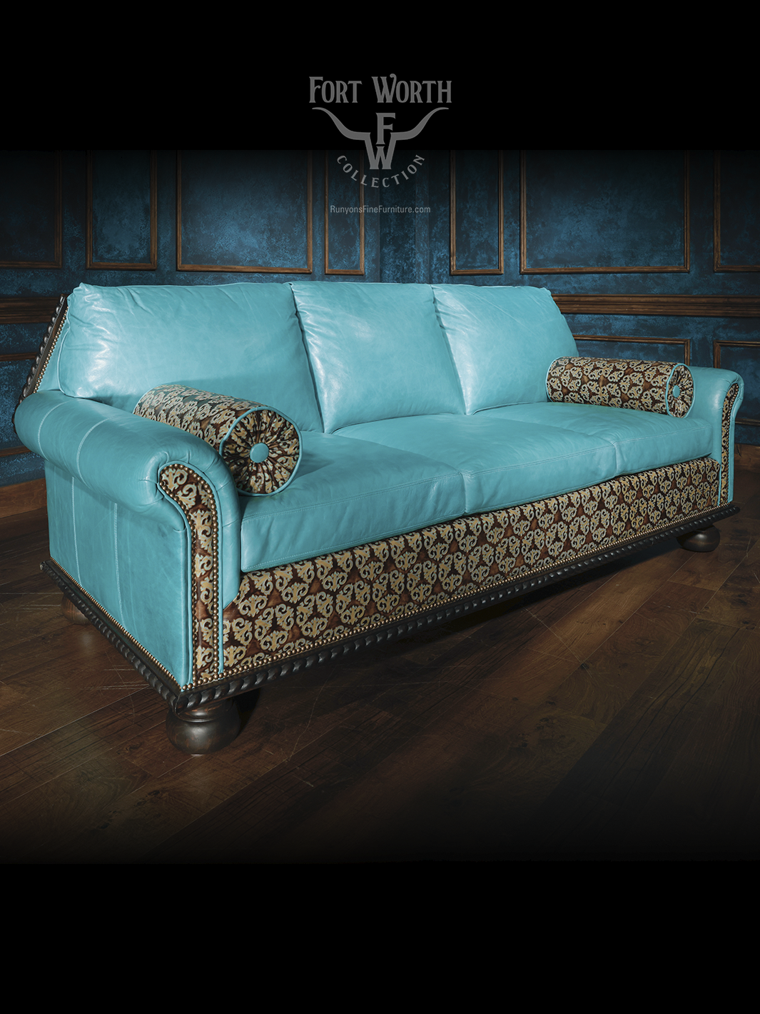 Full view of a turquoise leather western sofa with patterned fabric panels and bolster pillows, framed by nailhead accents and carved wooden base.