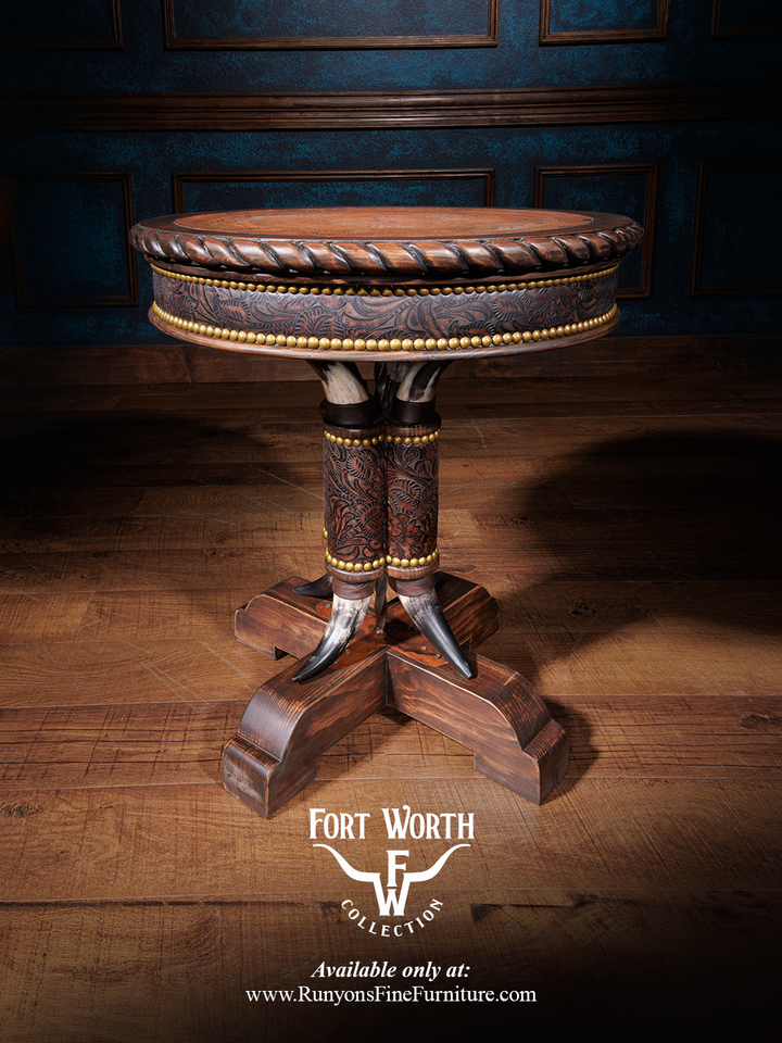 A handcrafted Western Steer Pedestal End Table with a copper inlay center, leather detailing, and wooden carvings, set against a blue wall and wooden floor background.
