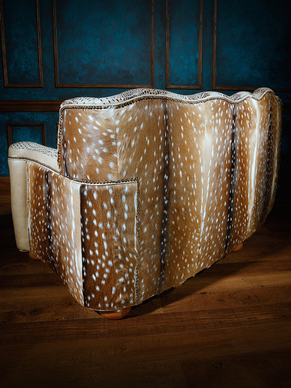 Back view of a Western-style sofa upholstered in authentic Axis deer hide with natural spotted pattern and hand-applied nailhead trim.