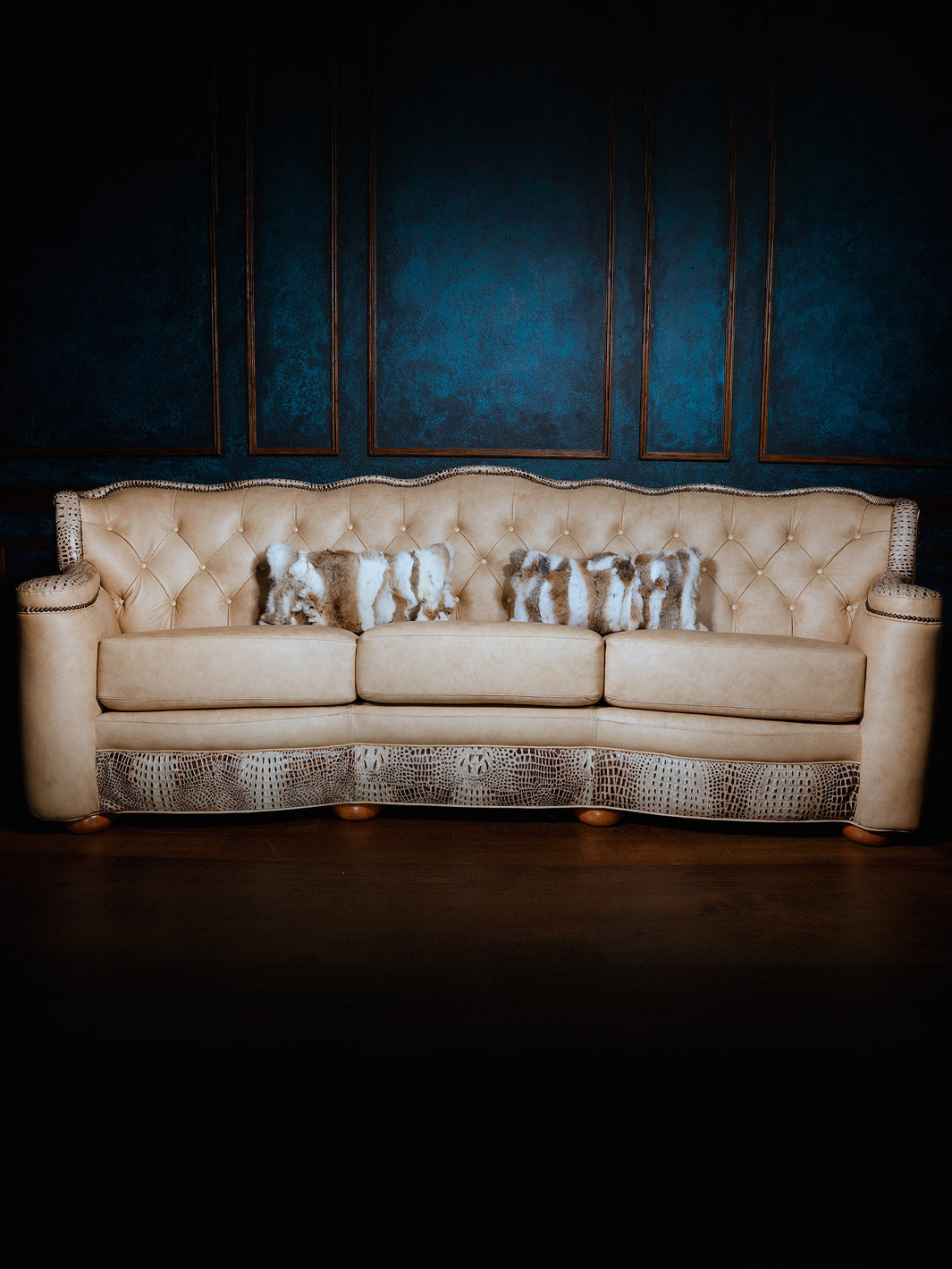 Full front view of a three-seat ivory leather sofa with crocodile-textured accents and tufted back cushions, styled with natural fur throw pillows.