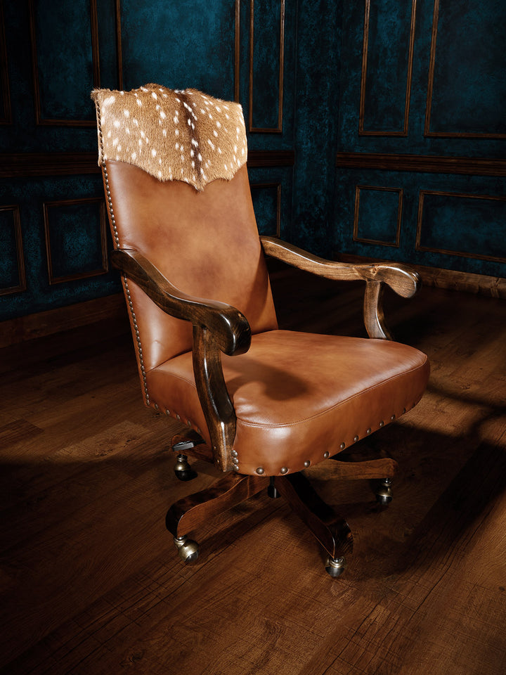 A brown leather desk chair with an axis deer hide yoke, alder wood frame, and honey color finish, upholstered and detailed for comfort.