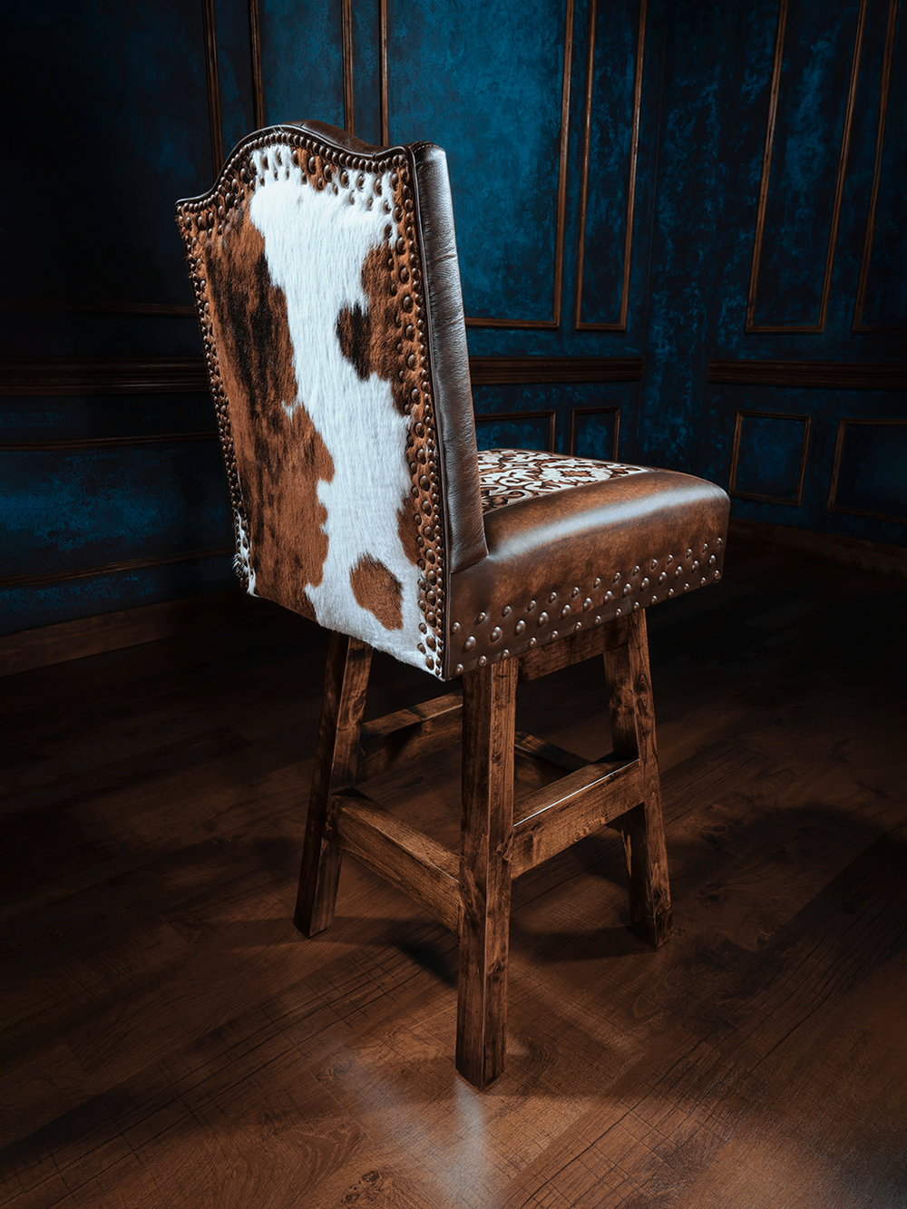Old Henry Armless Chisum Western Bar Stool with cowhide back, leather upholstery, and studded accents, showcasing rustic Western charm in a room setting.