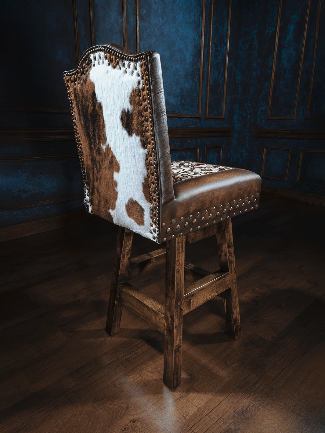 Old Henry Armless Chisum Western Bar Stool with cowhide back, leather upholstery, and studded accents, showcasing rustic Western charm in a room setting.
