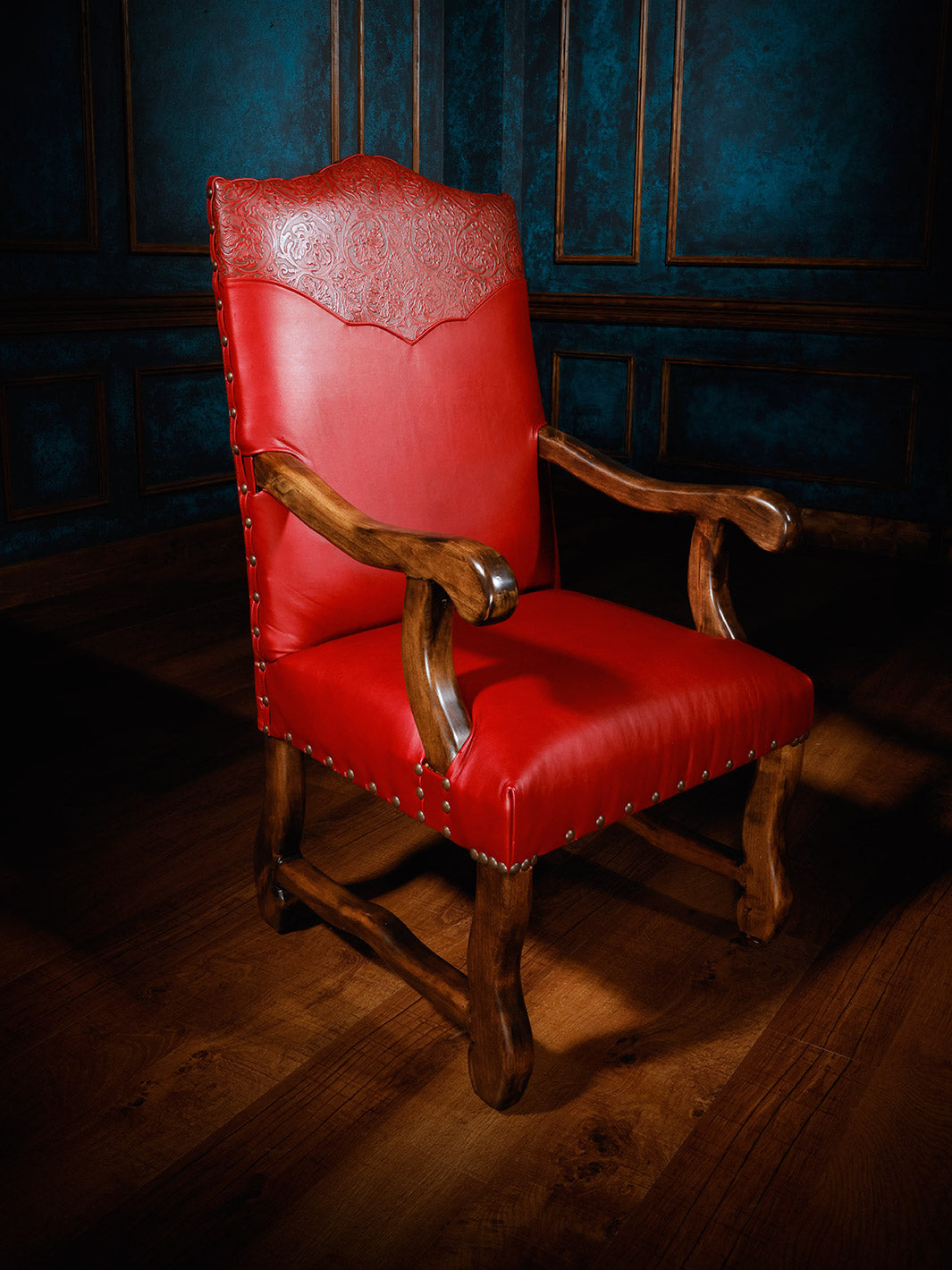 A red leather dining chair with a tooled leather yoke and brass nail heads, featuring an oak frame and high-density foam cushioning.