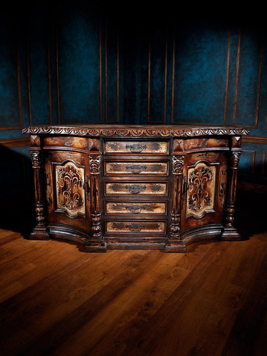 A brown wooden buffet with intricate carvings and a painted finish, placed against a dark blue background.