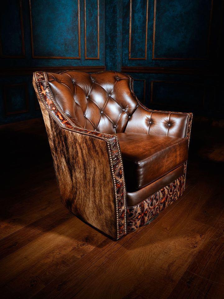 A brown leather swivel armchair with tufted backrest and a dark cowhide accent on the back and arm, set against a blue wall.