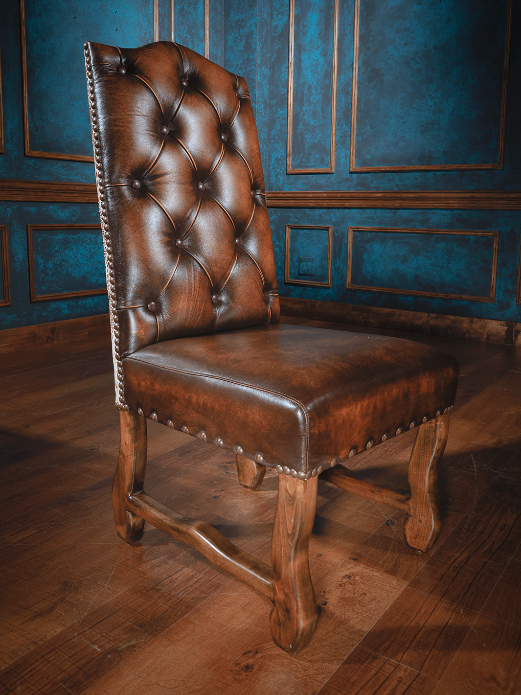 A luxurious brown leather dining chair with a tufted backrest and a crocodile pattern ivory gold finish back, displayed in a room with blue walls.