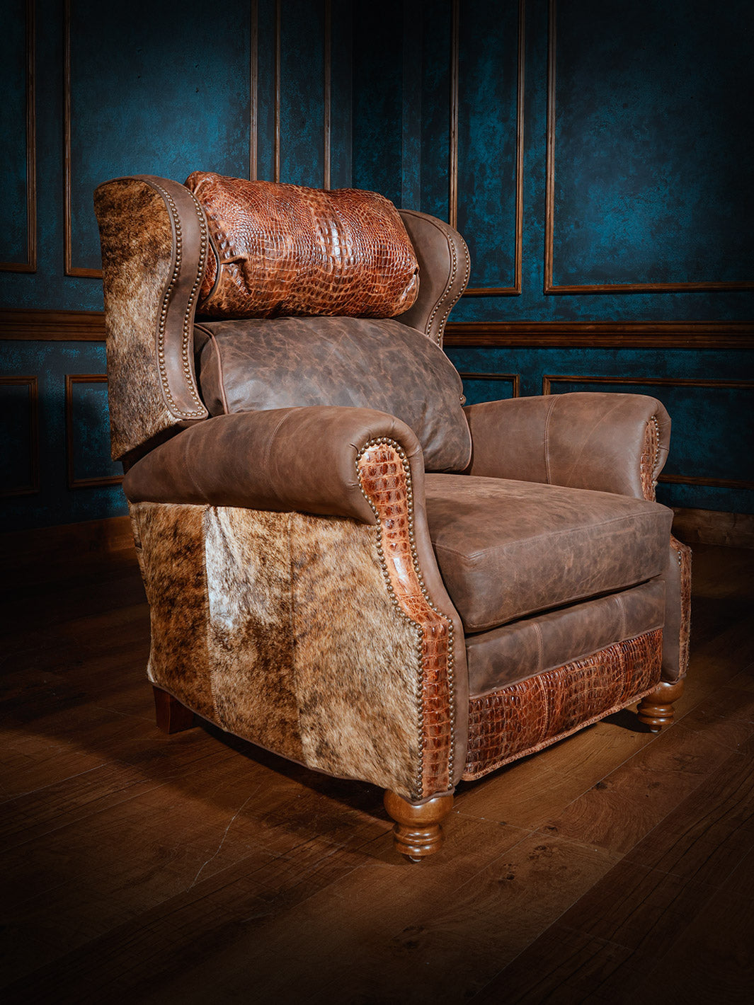 A luxurious western-style recliner featuring brown leather, a crocodile-patterned headrest, and cowhide-patterned sides, set against dark blue walls and wood flooring.