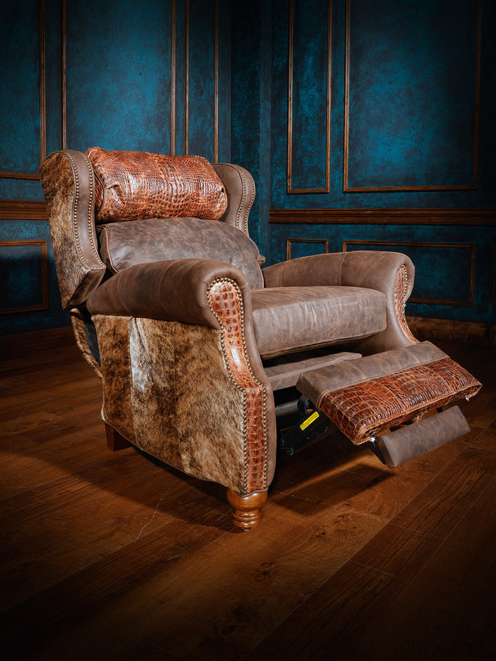 Western-style recliner with extended footrest, featuring brown leather, a crocodile-patterned headrest, and cowhide sides, set against dark blue walls.