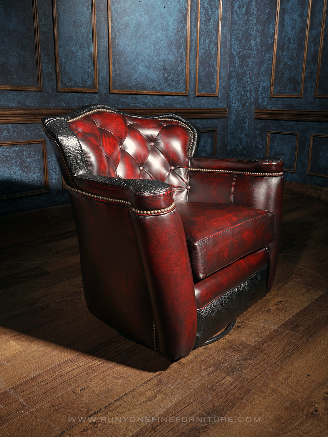 A red leather swivel chair with black crocodile trim and tufted buttons, placed in a room with blue panelled walls.