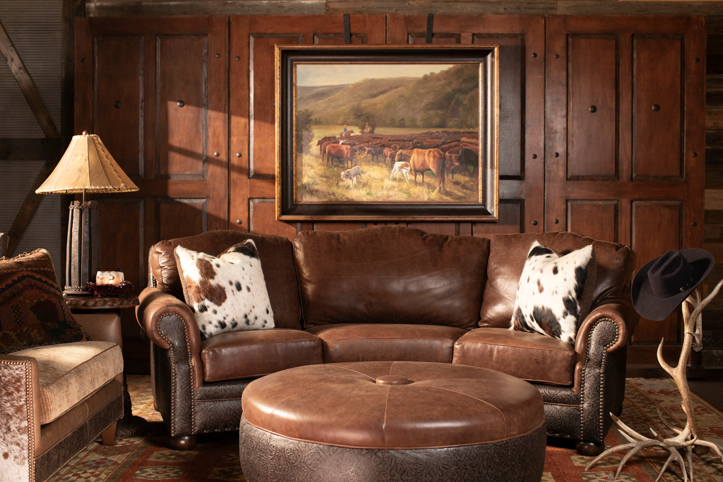 Western lounge scene with leather chair and ottoman, rustic wood side table, cowhide pillow, and warm ambient lighting