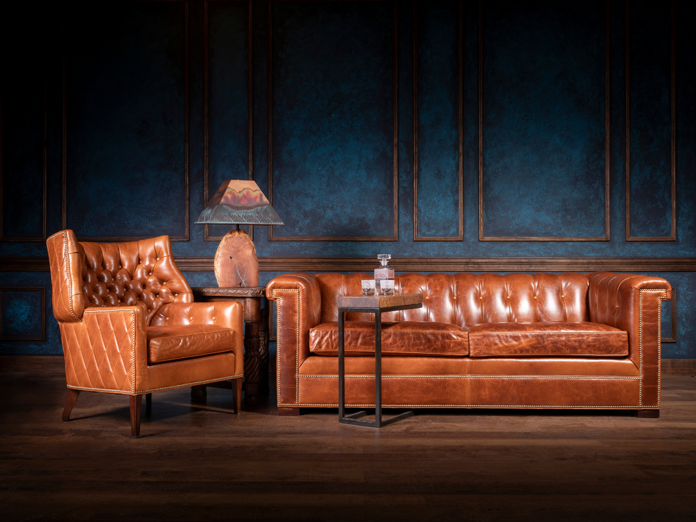 Tufted saddle leather sofa and chair with metal side table and stone lamp in a Modern Ranch lounge scene