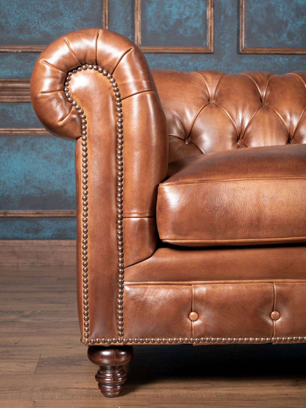 Close up of almond burnished leather Chesterfield sofa arm showing hand-tacked nailhead trim and rolled scroll arm detail