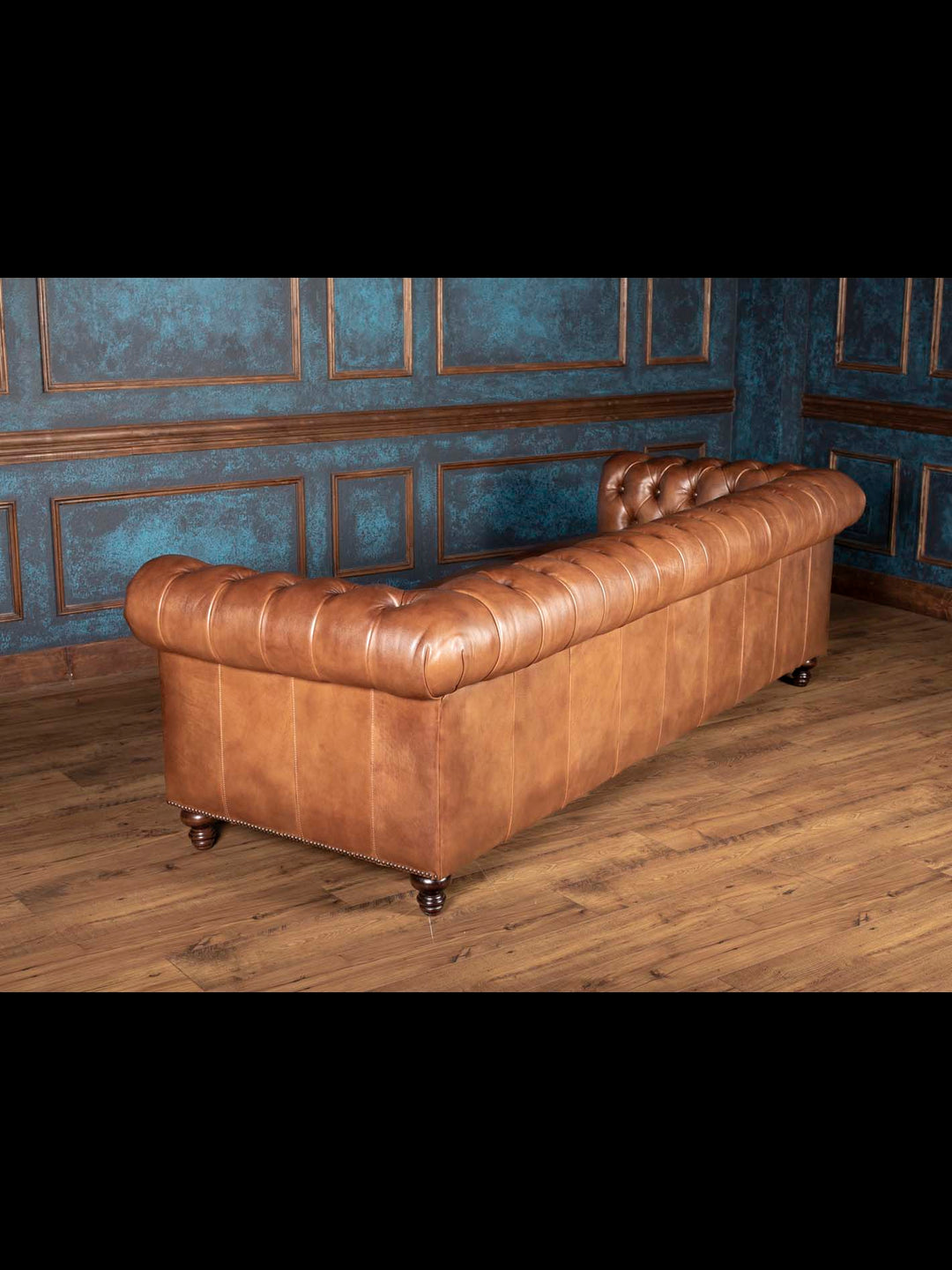 back view of almond brown leather Chesterfield sofa with smooth tailored leather panels and fully rolled top for upscale home décor