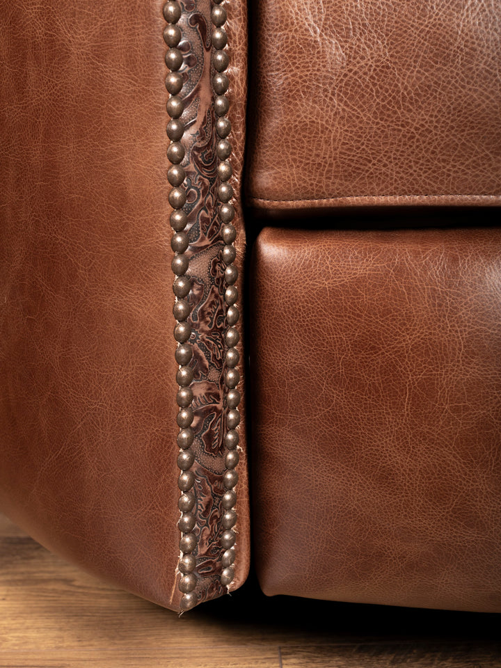 Detailed view of embossed leather and nailhead trim along recliner base