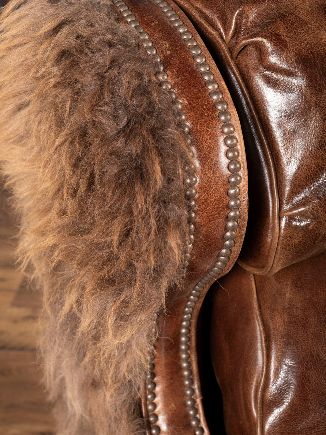 Close-up of brown recliner featuring hair on hide and nailhead accents