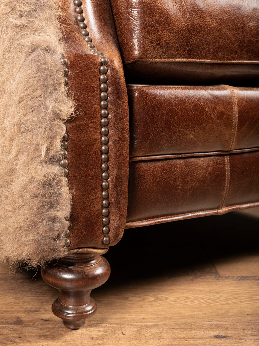 Close-up of a brown leather recliner with wooden legs