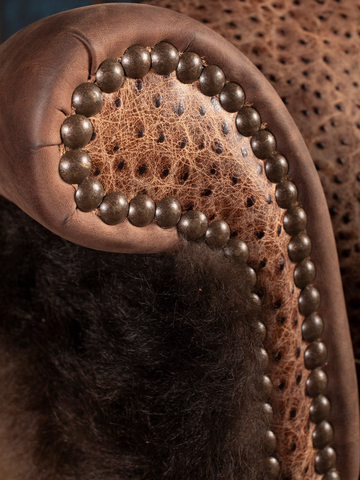 Close up of wingback chair with stamped leather accents and nailheads