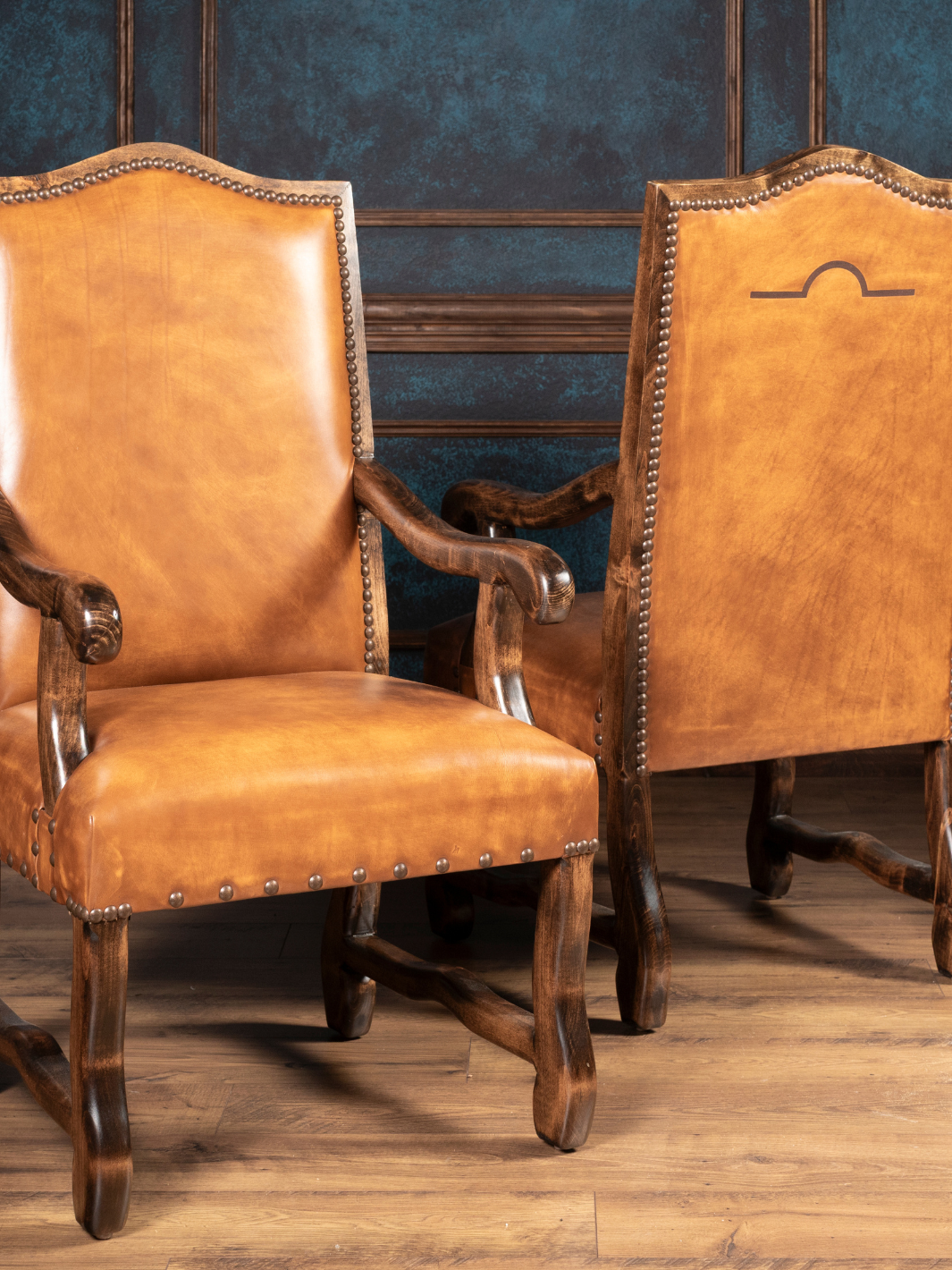 Pair of brown leather armchairs against a blue wall.