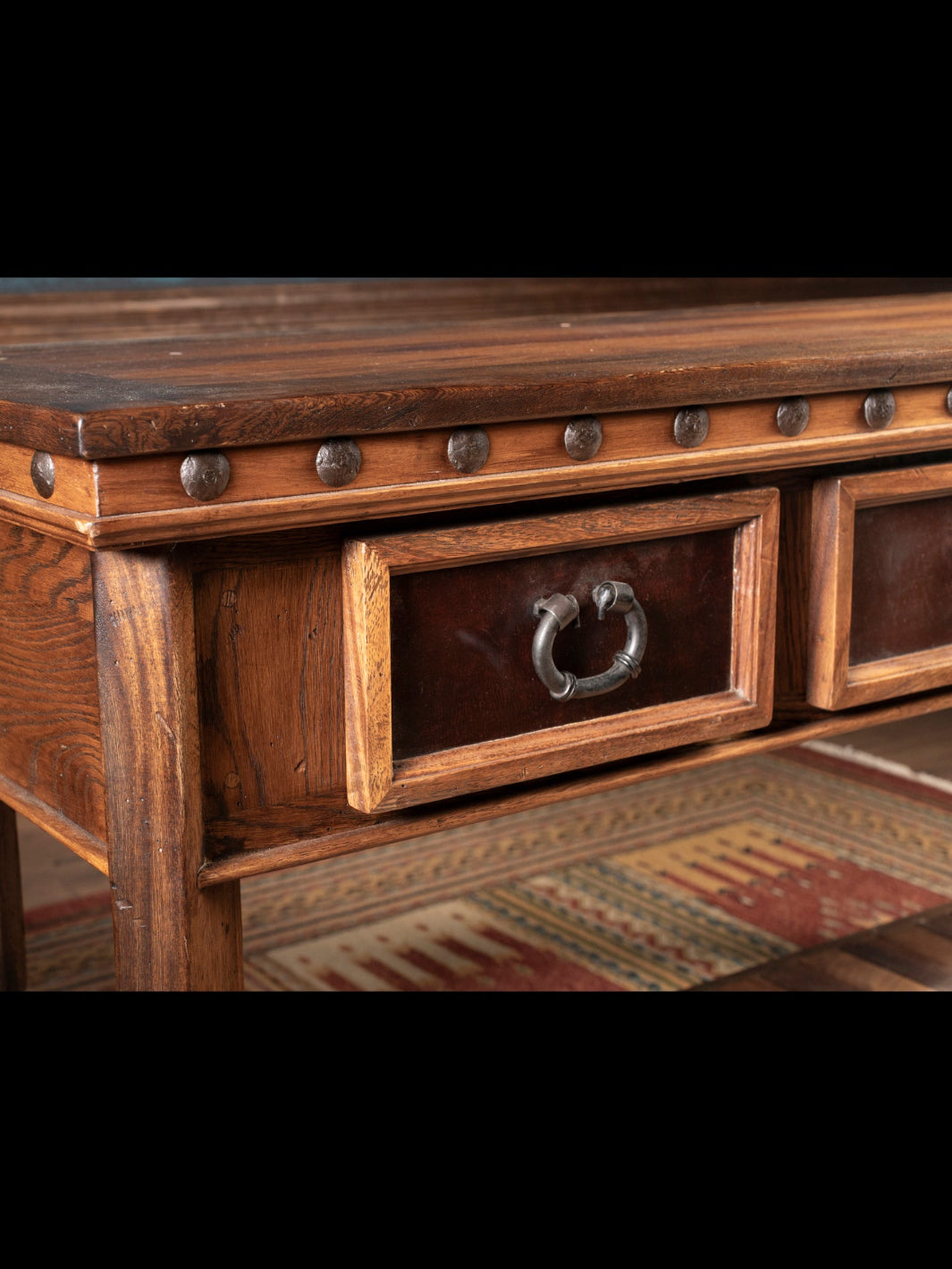 Wooden console table with metal accents on a patterned rug