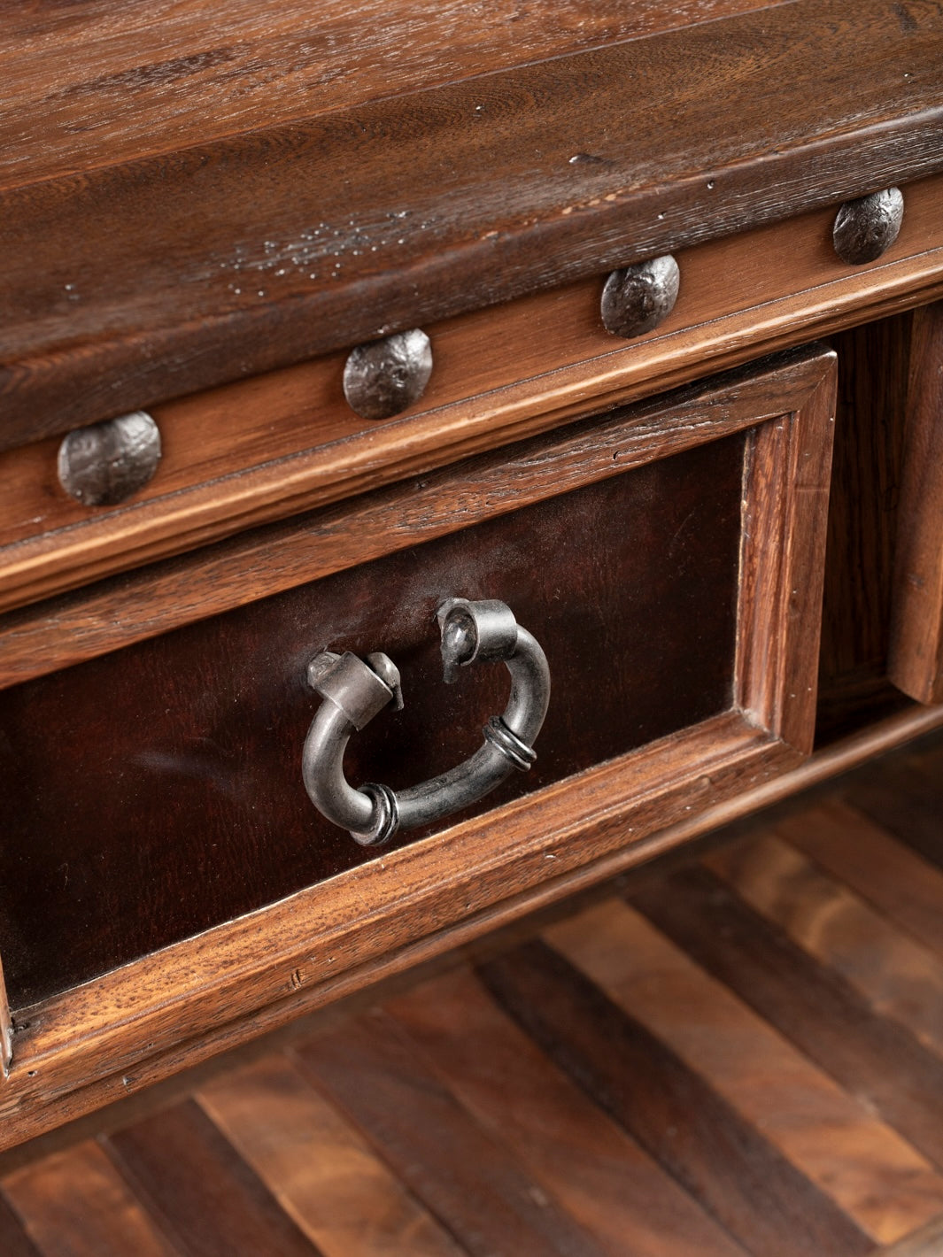 Close-up of a wooden drawer with metal handle and decorative studs.